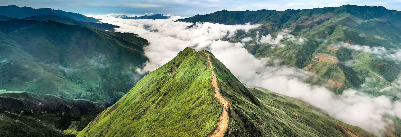 Green mountain ridge rising above the clouds