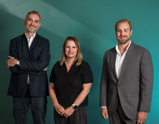 Three Essenta consultants, two men and a woman, standing against a teal backdrop