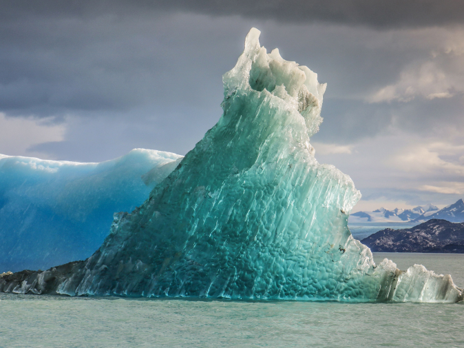 Iceberg rising from teal water