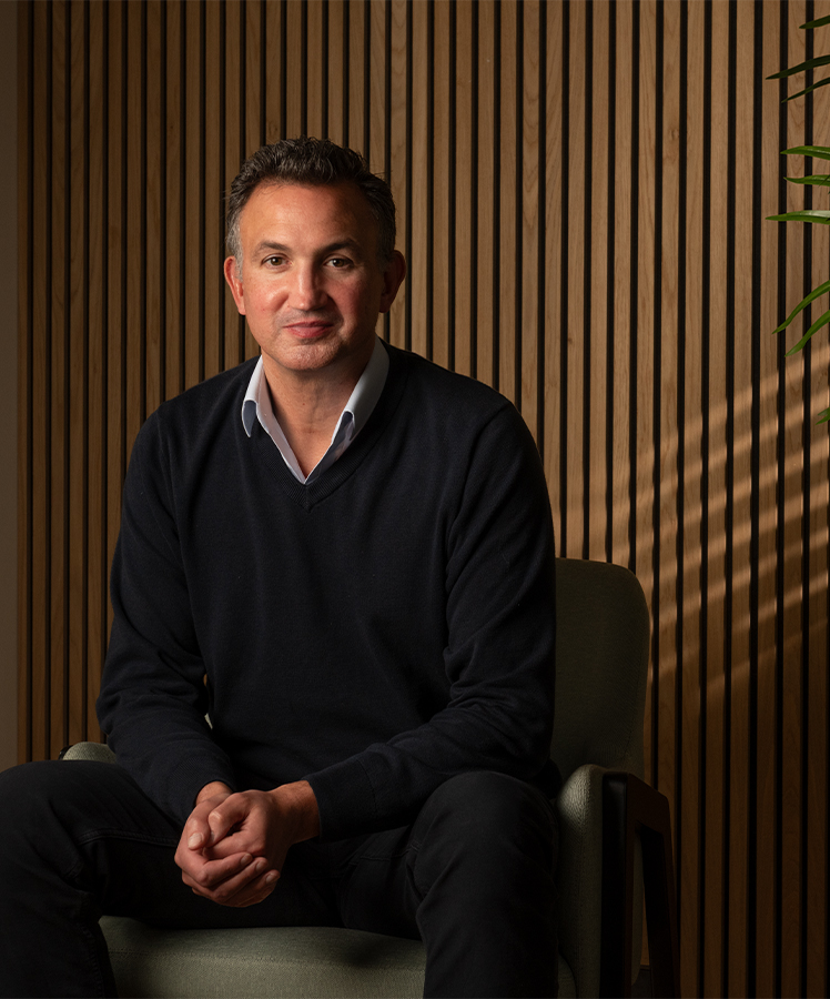 Essenta consultant in a dark suit standing in front of a timber slatted wall