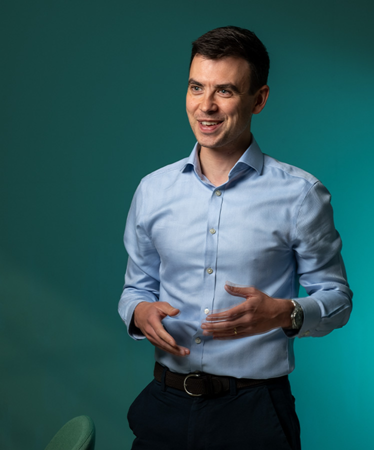 Smiling Essenta consultant in a light blue shirt against a teal backdrop